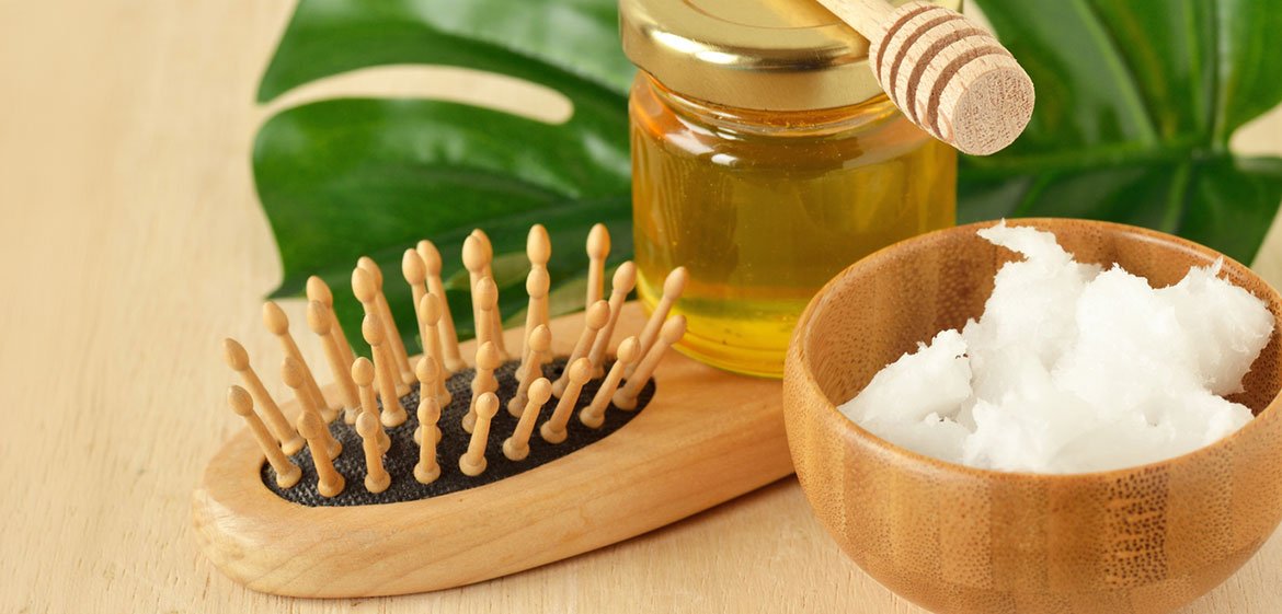 Stillleben mit Haarbürste, Tiegel mit Kokosfett und einem Glas mit einem Öl